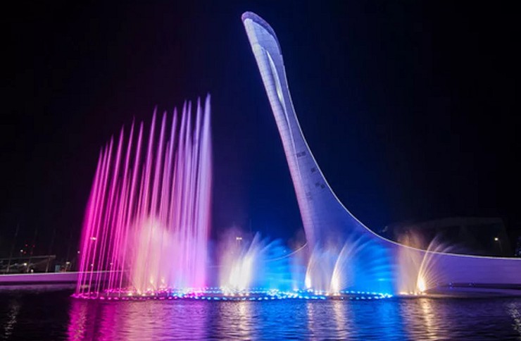Фонтан с подсветкой на фоне Олимпийского факела