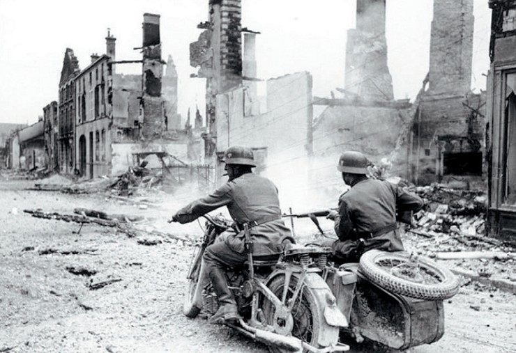 Немецкие мотоциклисты проезжают через разрушенный французский город. 1940 г.
