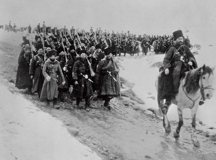 Офицер едет верхом по заснеженной дороге во главе колонны пеших казаков (пластунов) во время холодной зимы на Кавказе
