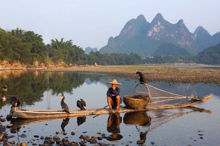 Местные рыбаки перемещаются по реке на бамбуковых плотах