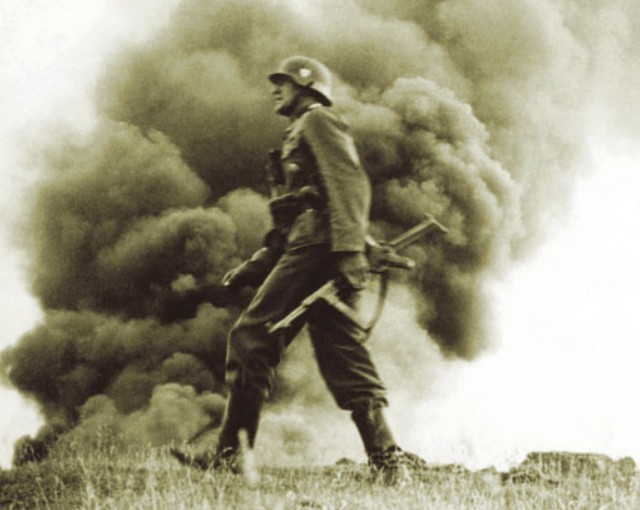 Немецкий офицер штурмовых войск во время нацистского вторжения в Советский Союз шагает на фоне горящих зданий