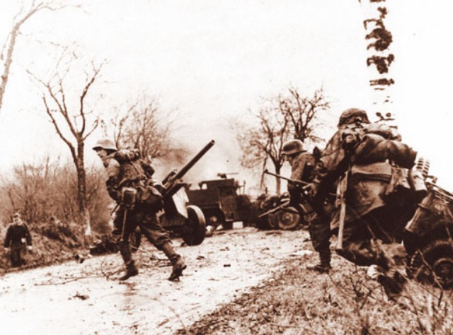 Немецкие солдаты пробегают мимо брошенной американской техники. Арденны. Декабрь 1944 г.