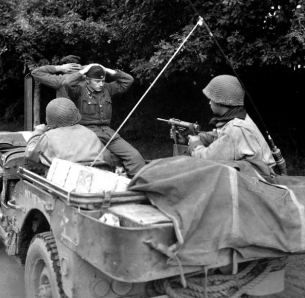 Американский патруль, вооруженный пистолетами-пулеметами М3, конвоирует пленных немецких солдат