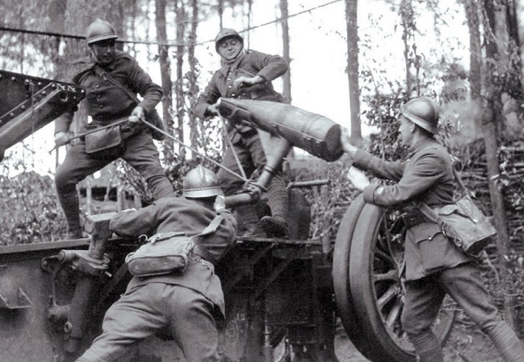 Французские солдаты заряжают артиллерийское орудие в лесу . 1940 г.