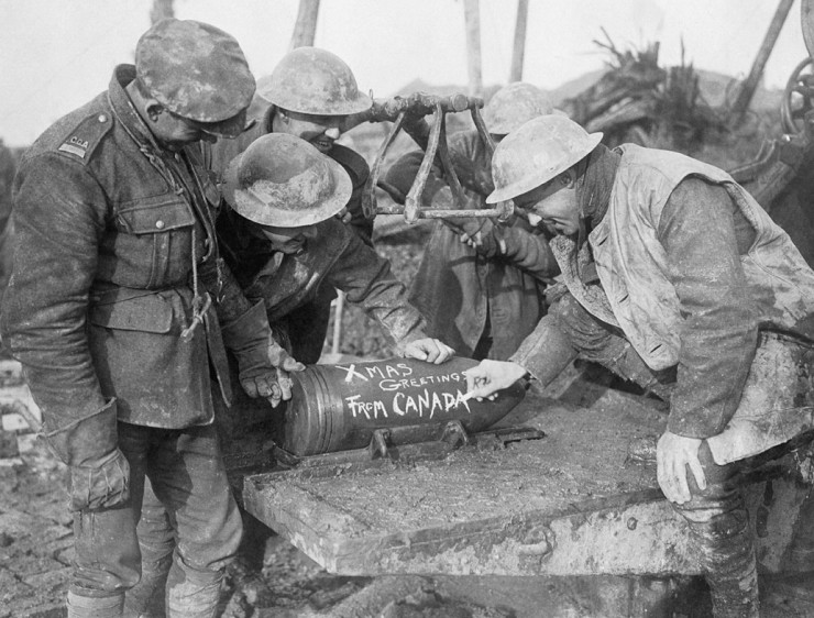 Канадские артиллеристы пишут мелом рождественское поздравление «бошам» по ту сторону нейтральной земли на крупнокалиберном артиллерийском снаряде, ноябрь 1916 г.