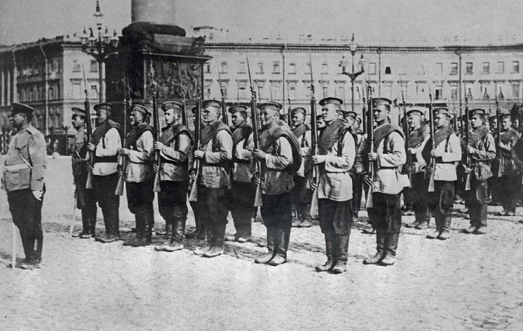 Солдаты одного из гвардейских полков стоят с винтовками «на караул» за спиной дородного офицера на Дворцовой площади в Санкт-Петербурге