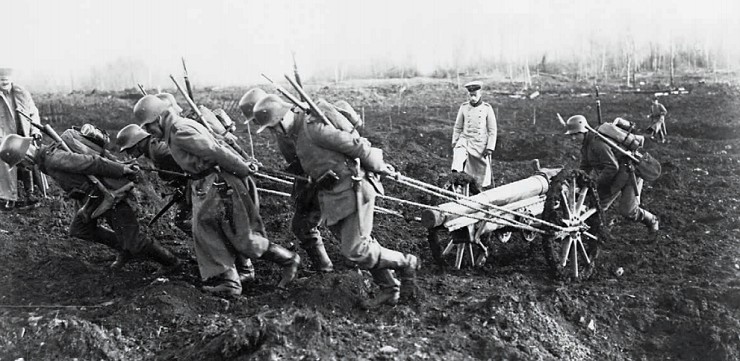 Германские артиллеристы тянут окопную пушку по полю, испещренному воронками от снарядов, 23 марта 1918 г.