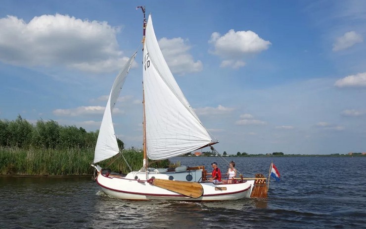 Аак под традиционными парусами и голландским флагом на озере в Фрисландии. Гроу, Нидерланды. 11 июля 2015 г.