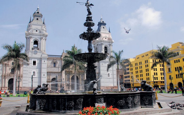Бронзовый фонтан на фоне кафедрального собора на площади Оружия в Лиме