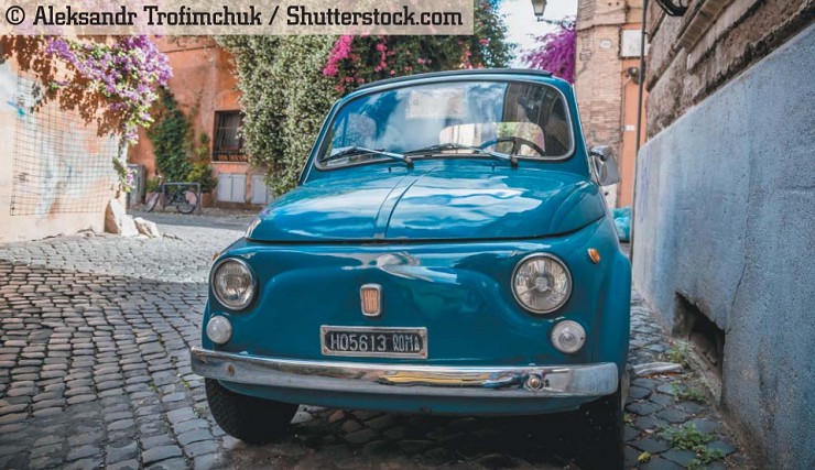 Старый городской автомобиль Fiat Nuova 500, припаркованный у стены с красивыми цветами на заднем плане. Рим, Италия, 27 мая 2014 г.